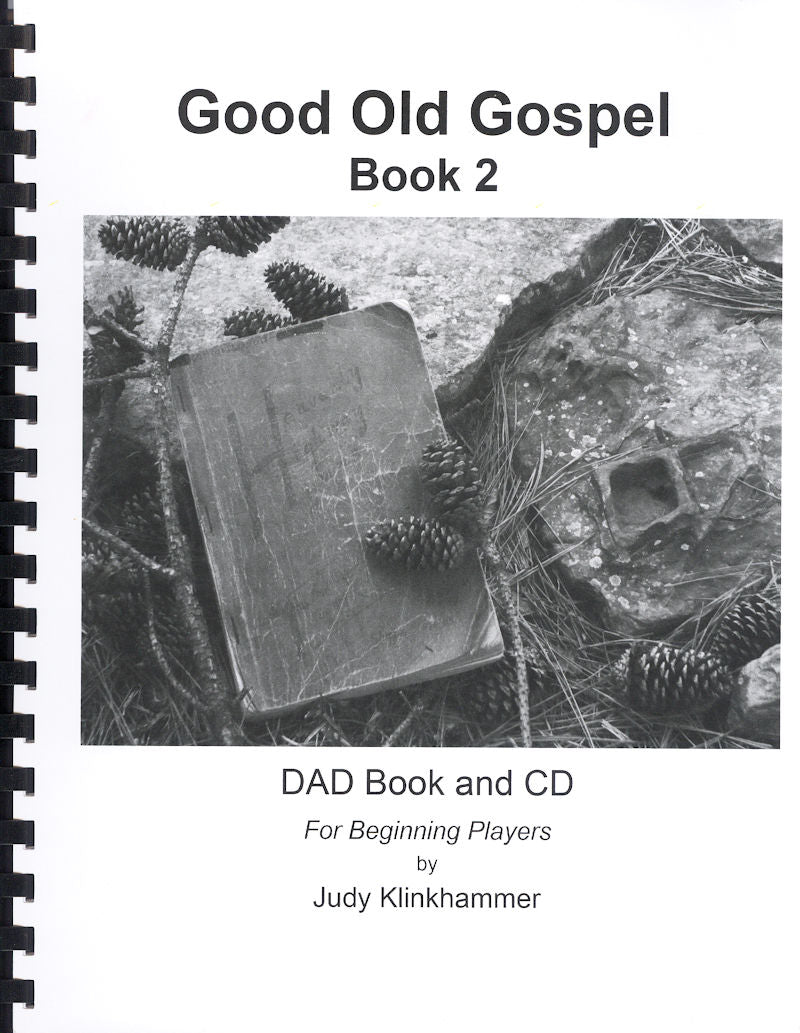 Cover of "Good Old Gospel, Book 2 - by Judy Klinkhammer." Ideal for beginners, it showcases a photograph of a worn book and scattered pine cones on a textured surface, embodying the spirit of Gospel Tunes in D-A-D tuning.
