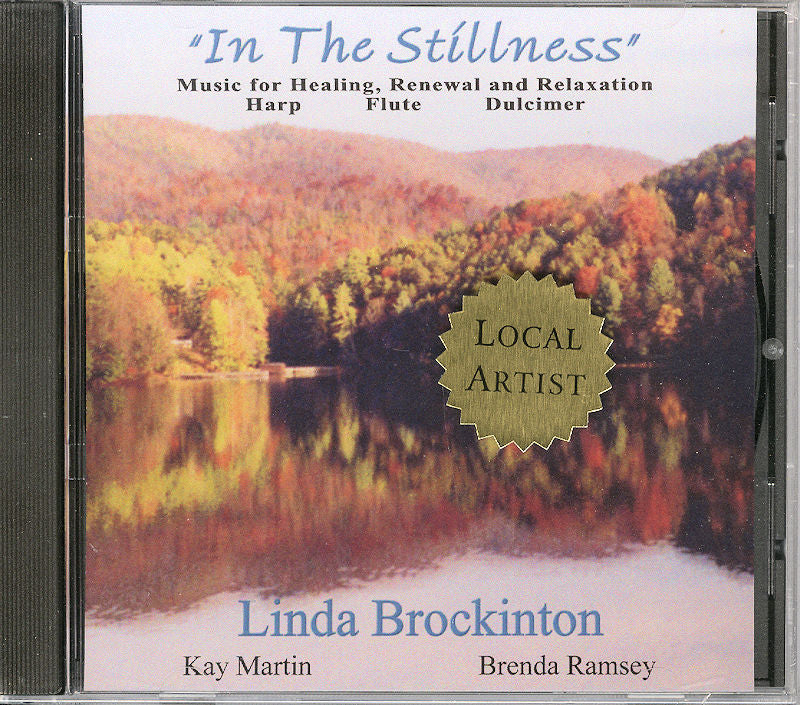 Cd case for "In The Stillness" featuring autumn forest reflection in lake, labeled "local artist". Music by Linda Brockinton, Kay Martin, Brenda Ramsey with harp, flute.