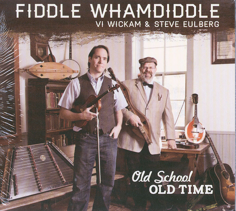 Two musicians stand in a room with instruments, their cover showcasing "Fiddle Whamdiddle by Vi Wickam and Steve Eulberg - Old School Old Time." With expert song choices, they guarantee an enjoyable listening experience rich in the charm of old-time music.
