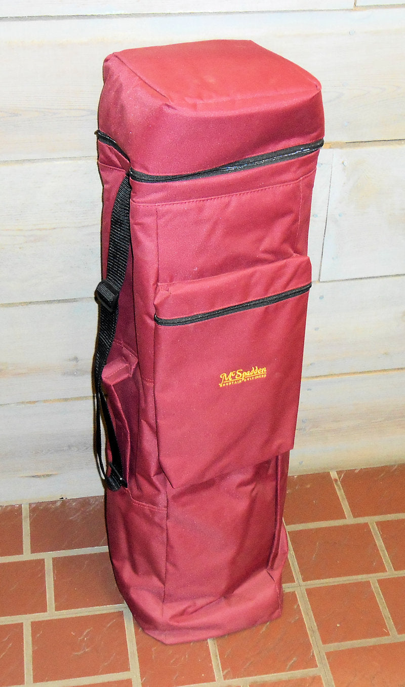 A burgundy Double Dulcimer Case is displayed upright on a tiled floor, featuring a padded divider, multiple pockets, and a sturdy carrying handle.