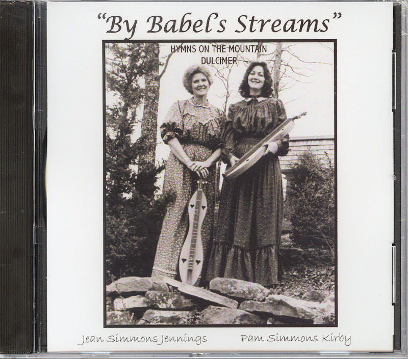 Two women dressed in period clothing stand outdoors, each holding a mountain dulcimer. This image is featured on the cover of the album "By Babels Stream by Dancing Doll," which includes 14 hymns performed on the mountain dulcimer.