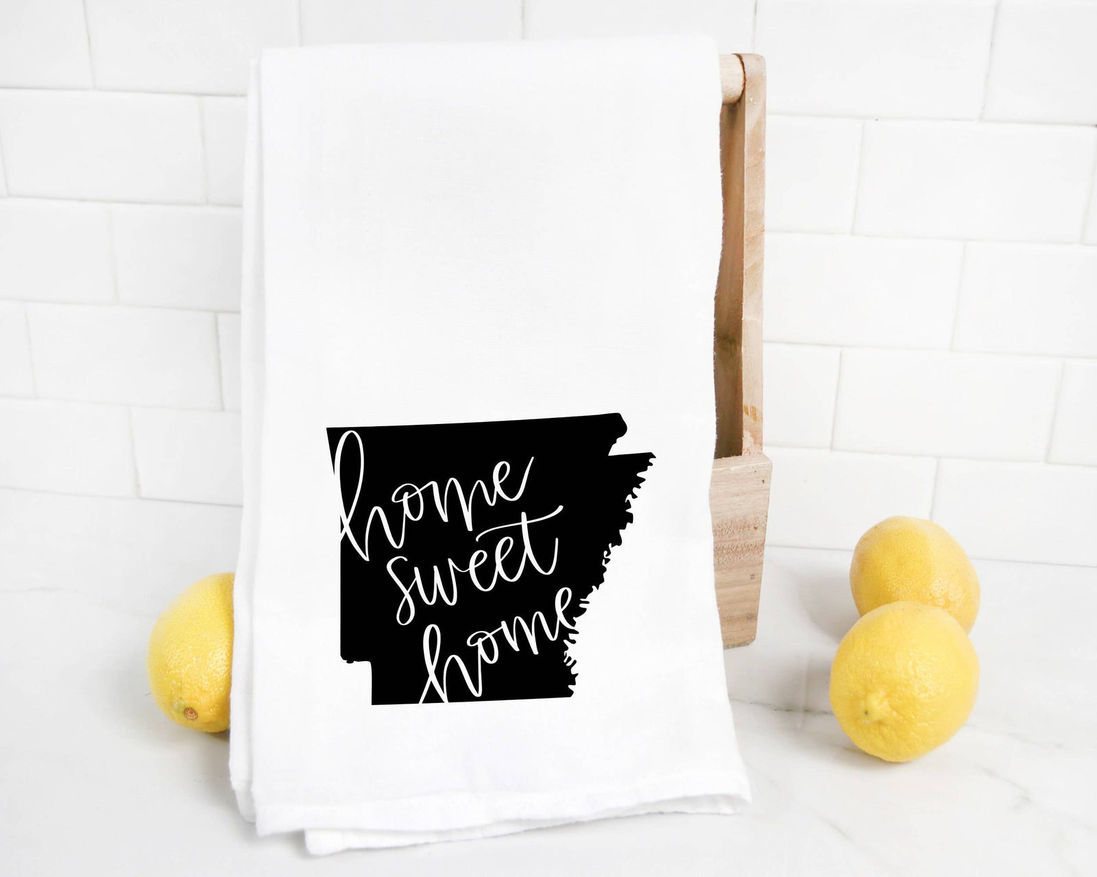 The discontinued Arkansas Tea Towel features a white flour sack with a black silhouette of Arkansas and "home sweet home" in cursive—ideal as a unique Arkansas gift.