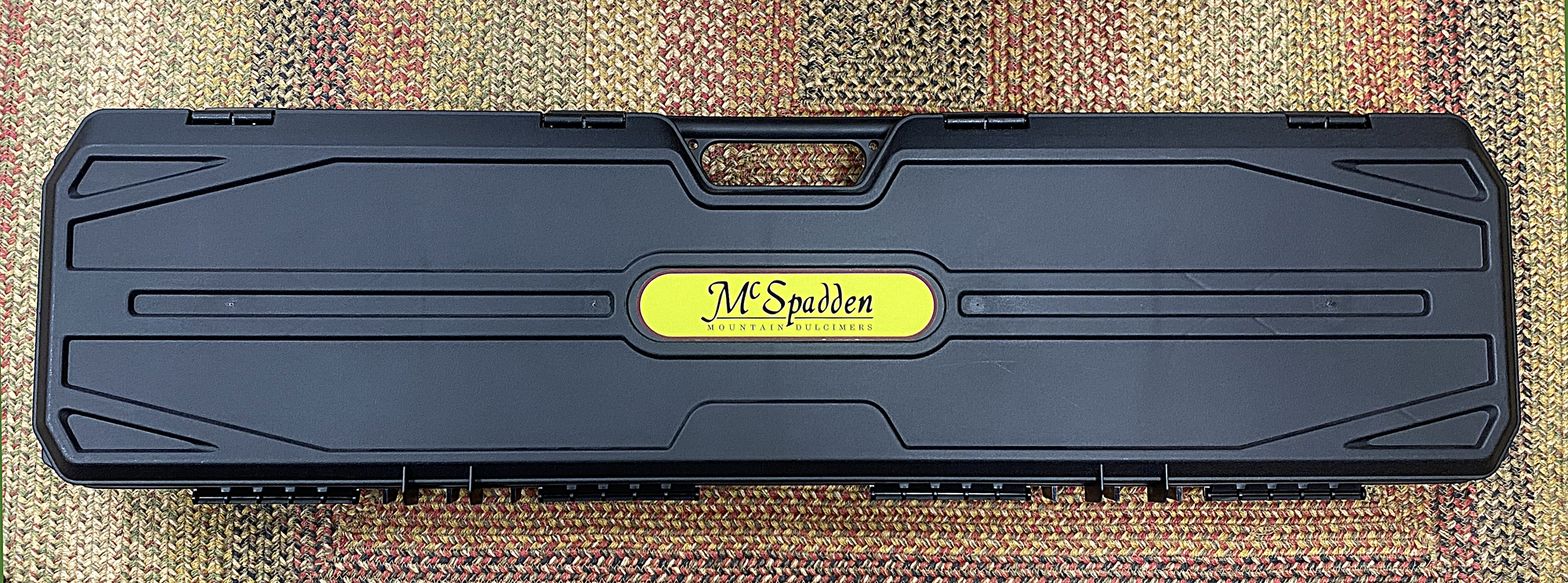 A black Hard Shell Dulcimer Case with a yellow label for dulcimer protection.