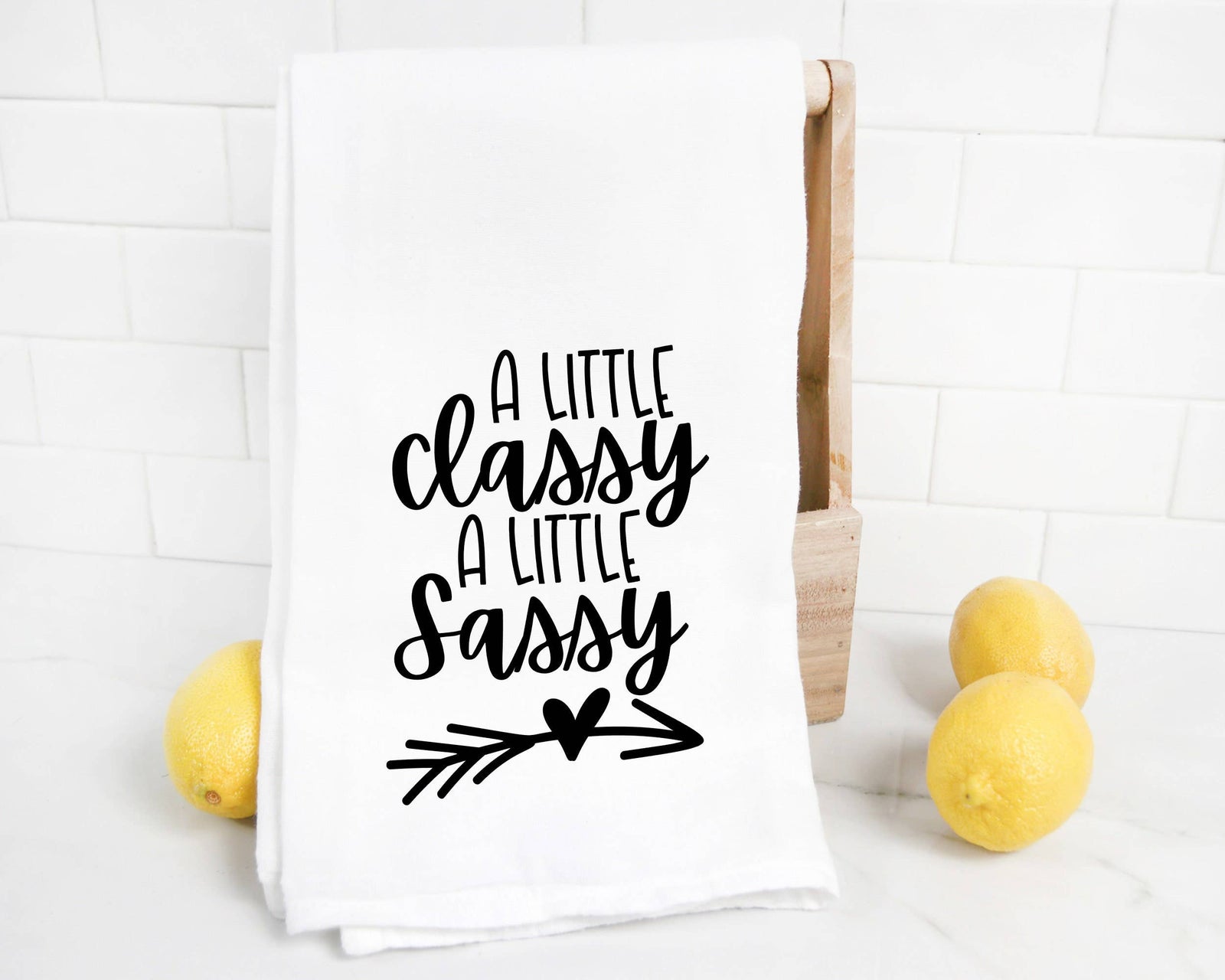 The discontinued Classy Sassy Tea Towel features "A little classy a little sassy" in black script on white—displayed with lemons, this funny kitchen towel makes a great birthday gift for her.