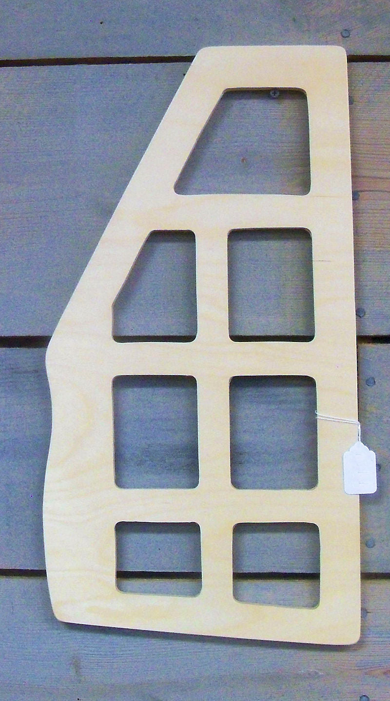 The Autoharp Backer Board Oscar Schmidt Model, resembling a window frame with multiple rectangular openings, is displayed against a wooden wall, reminiscent of an artist's autoharp standing silent. A small white tag is attached to the bottom right corner.